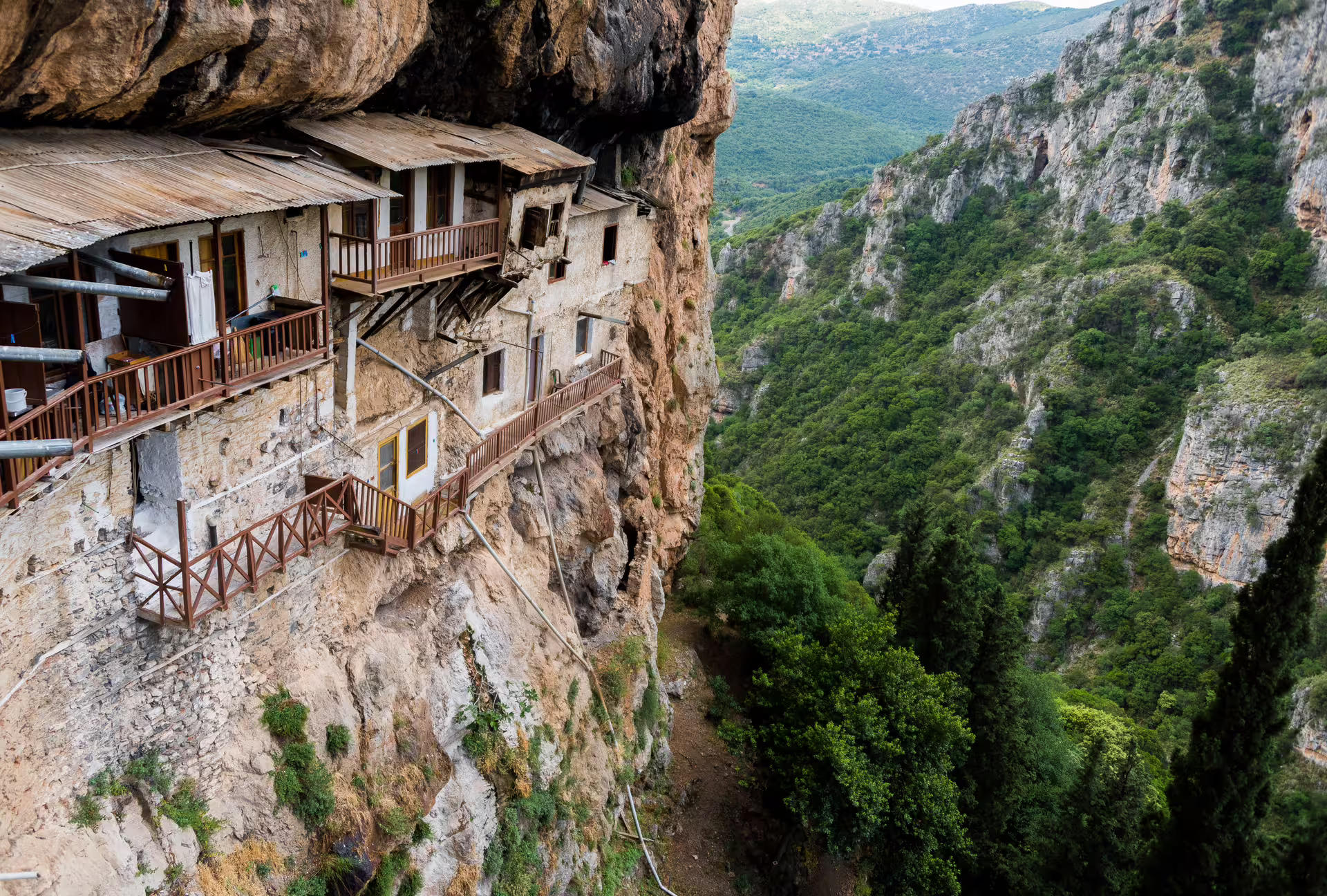 Close-up of Prodromos Monastery built into Lousios Gorge cliffs, dramatic canyon views on hiking tour