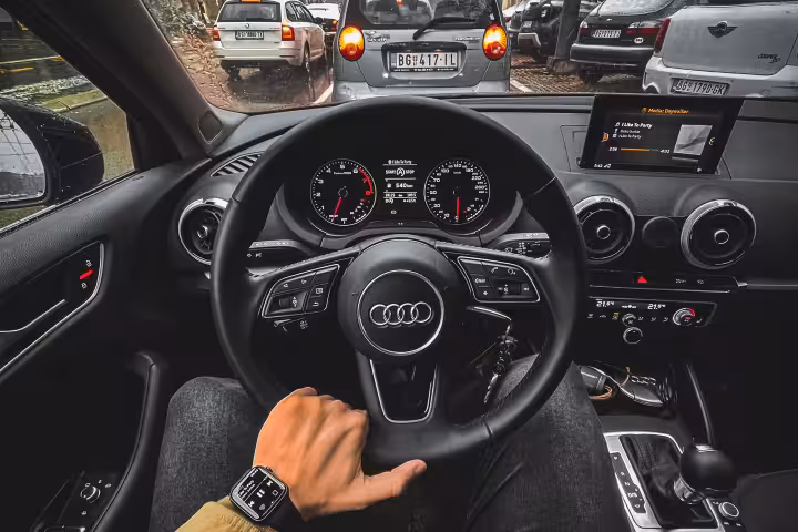 Professional chauffeur driving luxury Audi through busy city traffic, showcasing premium private car service in Muscat