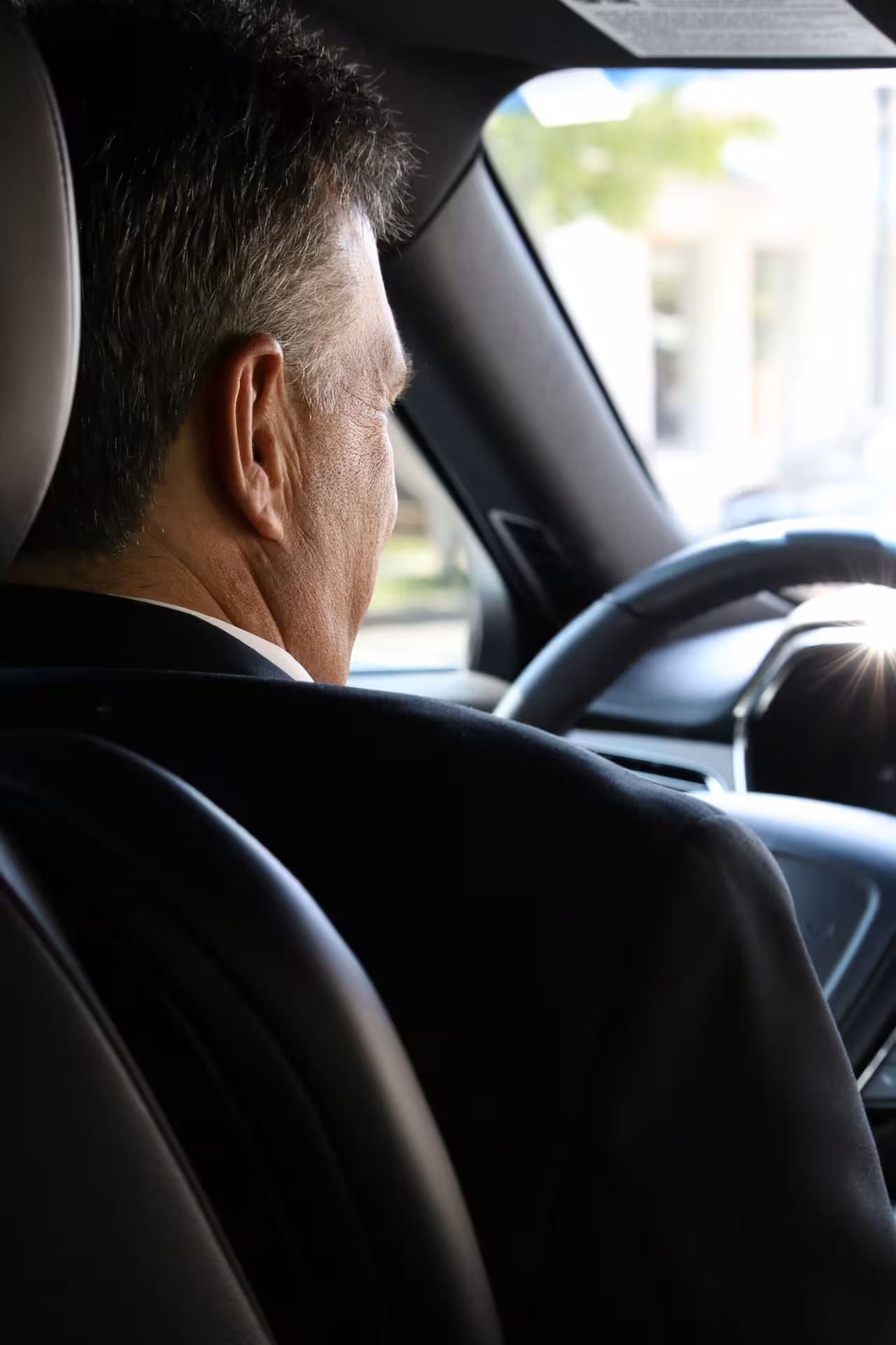 Professional chauffeur in suit driving premium car, offering reliable Muscat private transfers and corporate car service