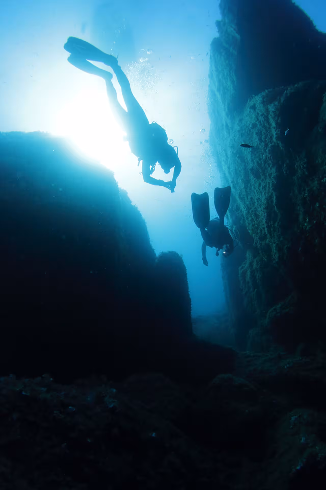 Diver navigates through underwater rock formations in Tavolara, highlighting adventure in San Teodoro's marine life.