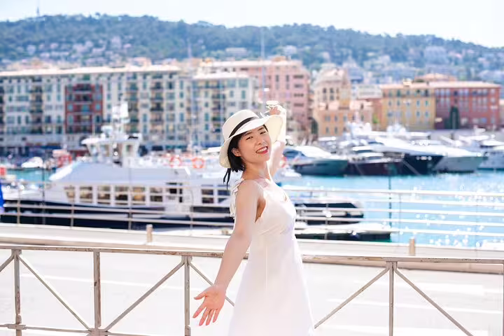 Woman in white dress and hat enjoys a sunny day at Cannes harbor, perfect for a professional photoshoot experience.