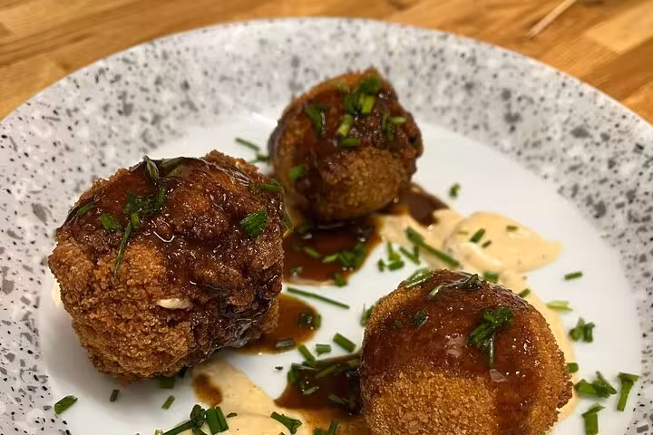 Provençal cooking class in Marseille featuring crispy croquettes with rich sauce and herbs on a speckled plate