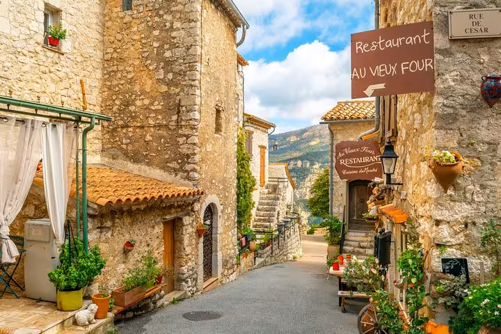 Charming medieval village street with stone houses and a cozy restaurant in the Provencal region.