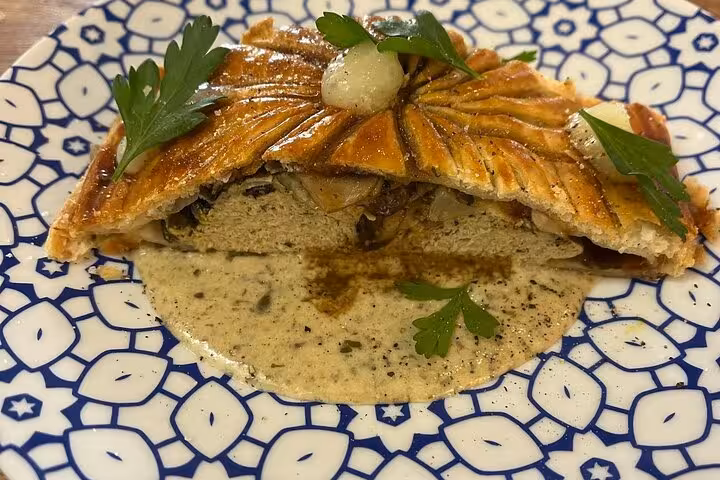 Slice of savory Provençal pie with creamy sauce, prepared in a Marseille cooking workshop with a local chef