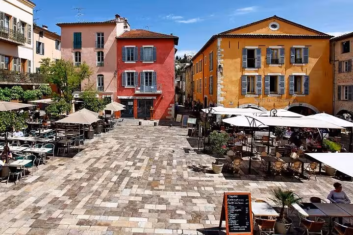 Sunny Provençal village square with outdoor café terraces and colorful facades near Cannes
