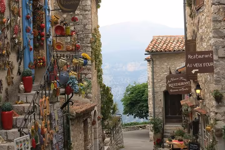 Colorful artisan shops and restaurant on a narrow stone street in a Provençal hilltop village with mountain views