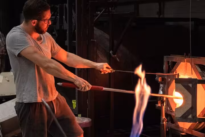Artisan demonstrating traditional glassblowing techniques with fiery kiln in a Provence countryside workshop.