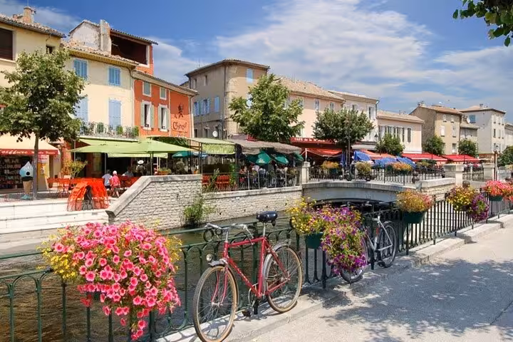 Picturesque canal-side cafes in Provence with vibrant flowers and bicycles, ideal for a relaxing stroll.