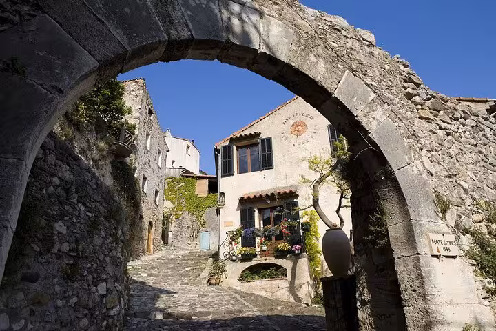 Historic stone archway framing a quaint house in the picturesque Provence countryside village.