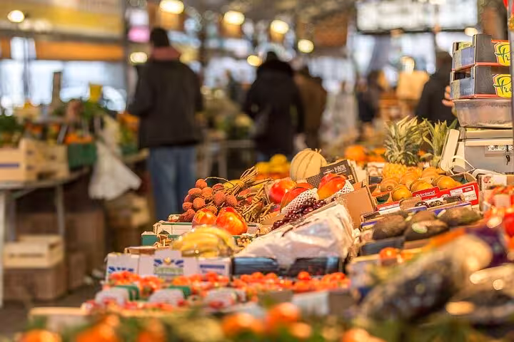 Colorful fresh fruit and vegetable market stall in Provence, France with shoppers in background