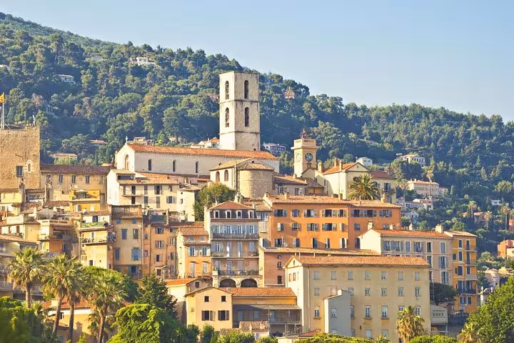Charming hillside village in Provence with historic architecture and lush greenery on a sunny day.