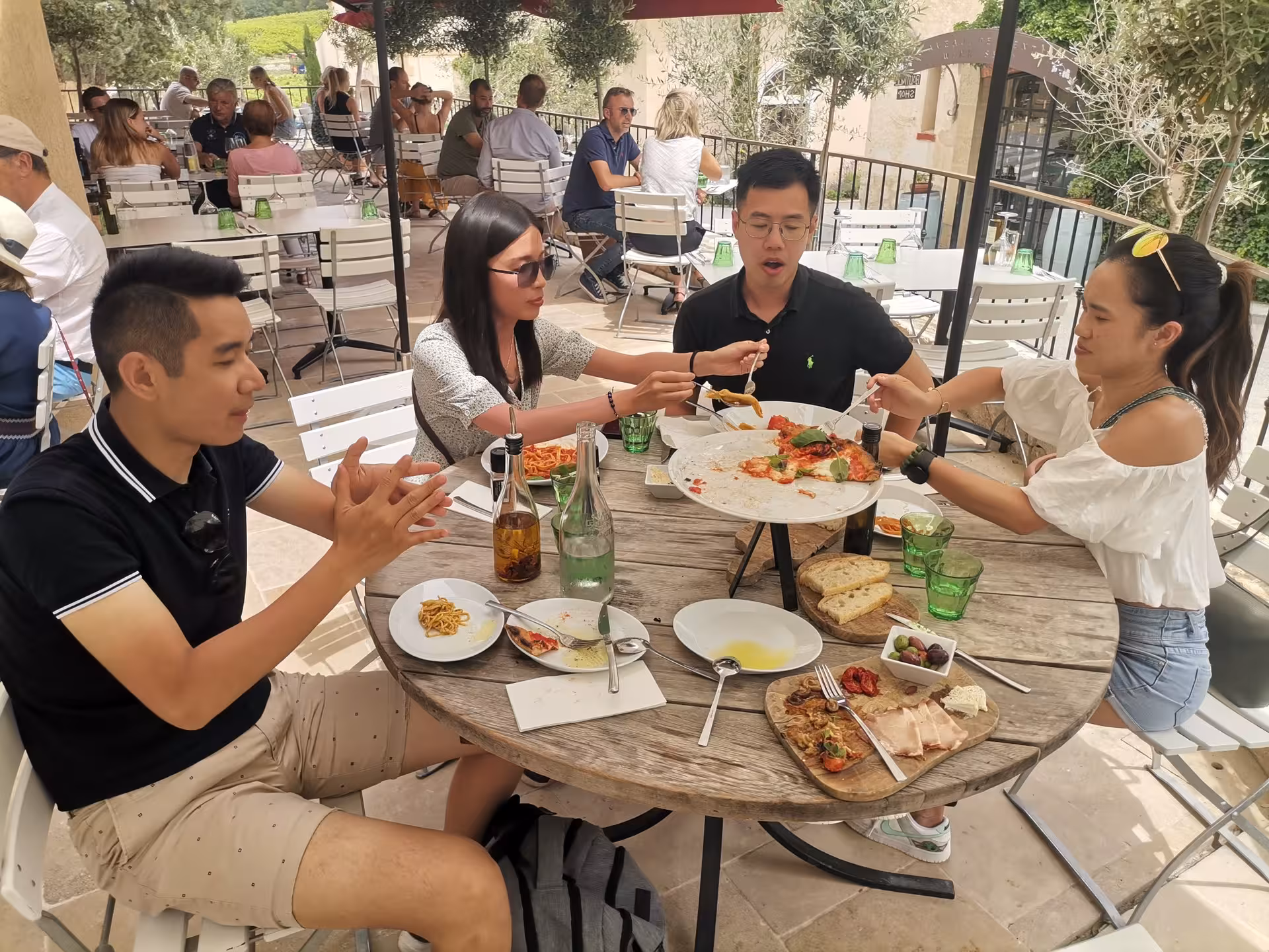 Travelers sharing lunch on a shaded terrace after a Provence lavender field tour, enjoying local food and wine