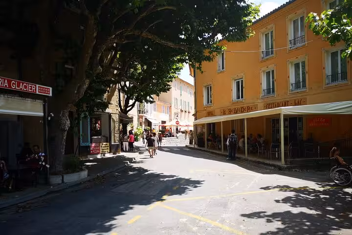 Shaded Provençal village street with cafes and pastel buildings, stop on a private full-day lavender tour
