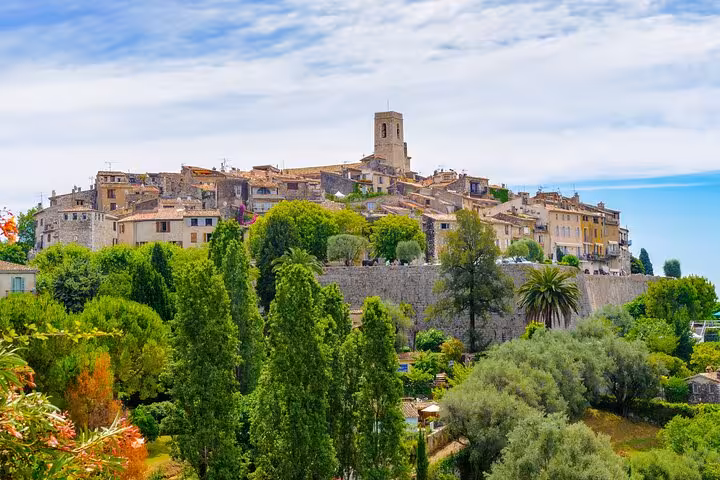 Medieval hilltop village with stone buildings and church tower surrounded by lush greenery in Provence, France