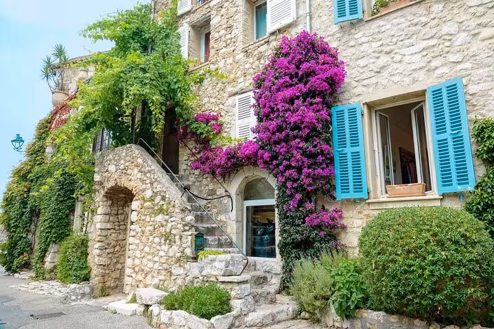Stunning medieval stone building with purple bougainvillea and blue shutters in a Provence village tour