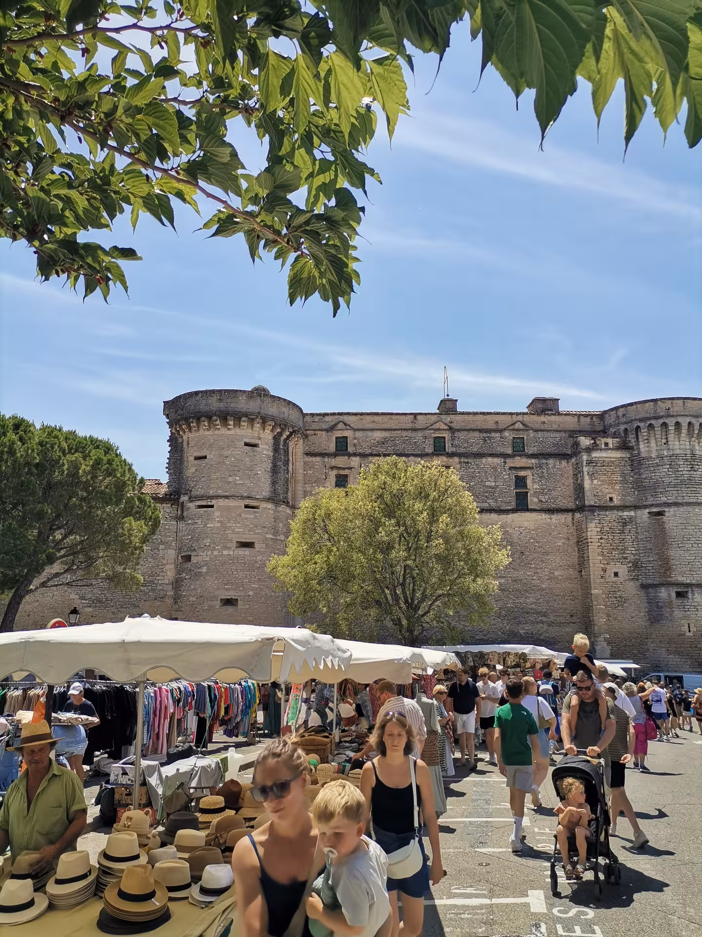 Provence street market by a historic stone fortress, ideal stop on a Provençal Picnic Tour with local finds