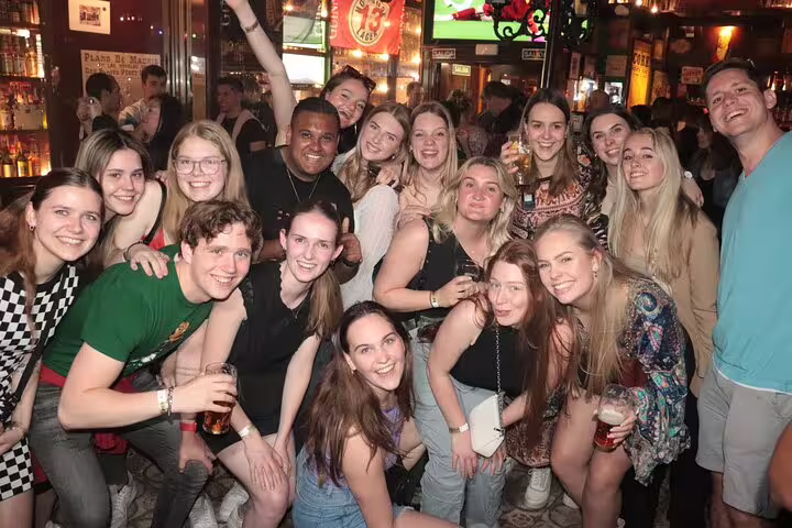 Large group of young adults having fun at a busy bar during a Madrid pub crawl tour, highlighting social nightlife experience.