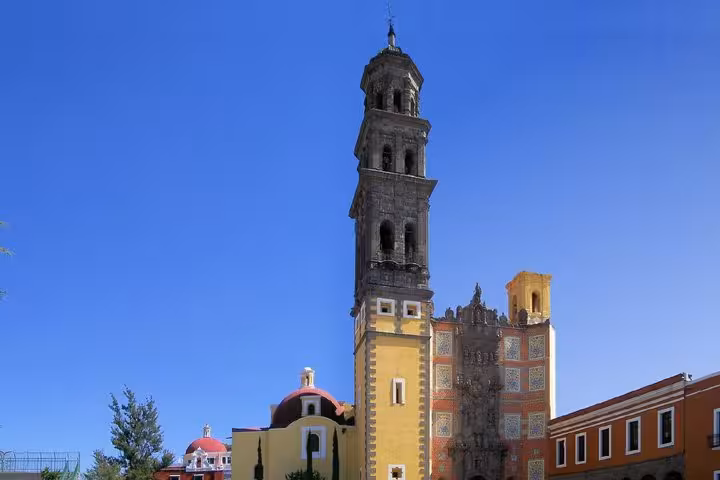 Tall baroque bell tower of a colonial church with colorful facades in Puebla, Mexico