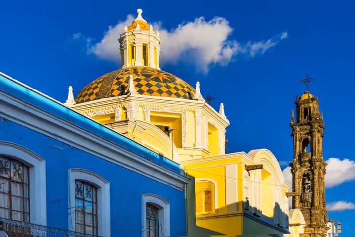 Colorful colonial church with checkered yellow dome and bell tower in Puebla, Mexico
