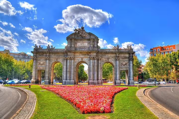 Puerta de Alcalá triumphal arch with red flowers in Madrid city center