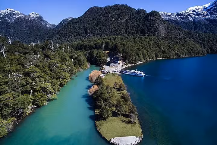 Aerial view of Puerto Blest with a lush peninsula dividing two sparkling lakes amid forested mountains.