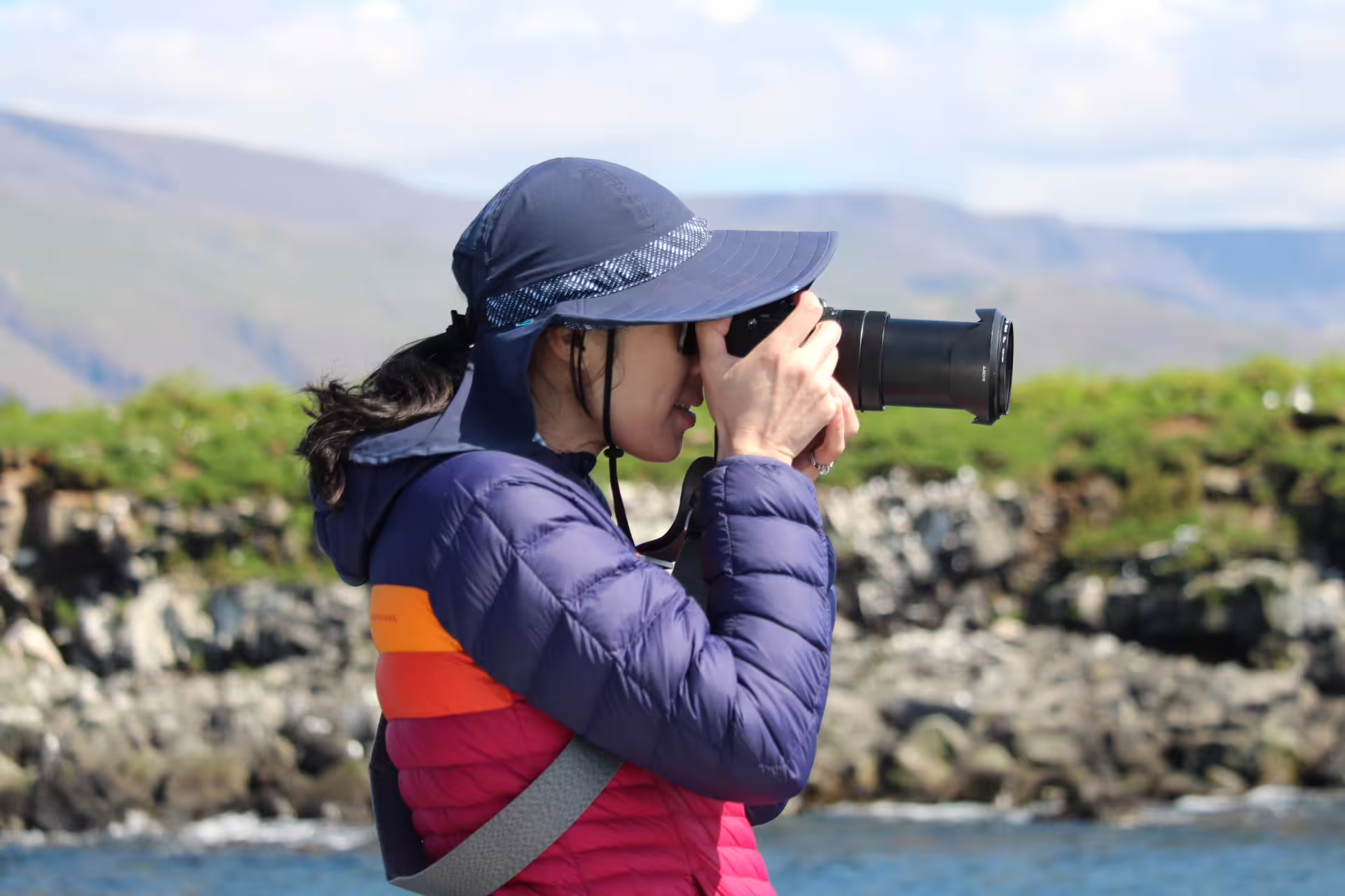 Tourist photographing puffins with telephoto lens on a scenic Reykjavik island boat tour in Iceland