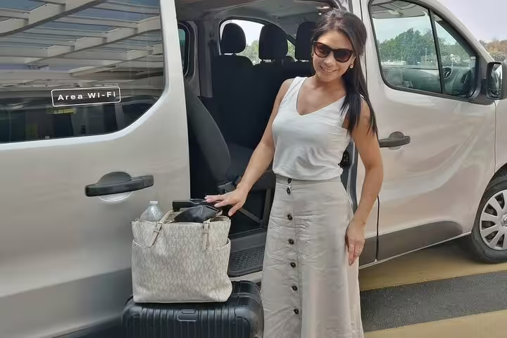 Smiling traveler loading luggage into a private Wi-Fi transfer van from Punta Cana Airport to Puerto Plata.