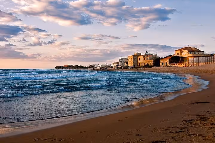 Sunset view of Punta Secca beach with historic buildings, famous for Il Commissario Montalbano tours in Sicily.