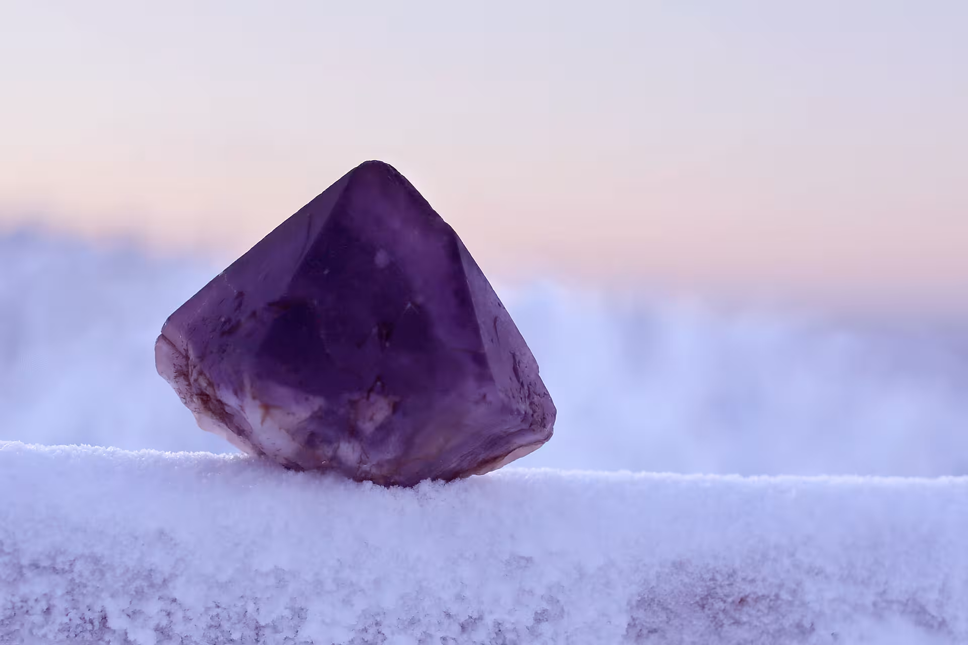 Close-up of a purple amethyst crystal on snow, highlighting the gemstone treasure from Lapland's winter mine tour.
