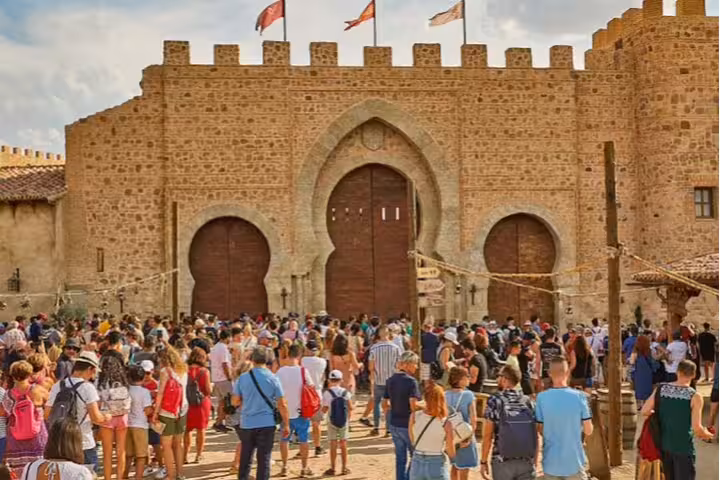 Crowds entering Puy du Fou medieval fortress gates, private minivan transportation for hassle-free arrival