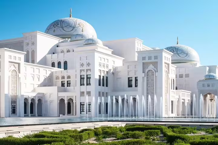 Majestic white facade and domes of Qasr Al Watan in Abu Dhabi with fountains and gardens seen on a guided city tour