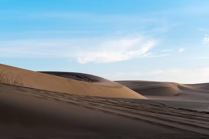 Sweeping Qatar desert sand dunes with dramatic shadows perfect for dune bashing safari adventure