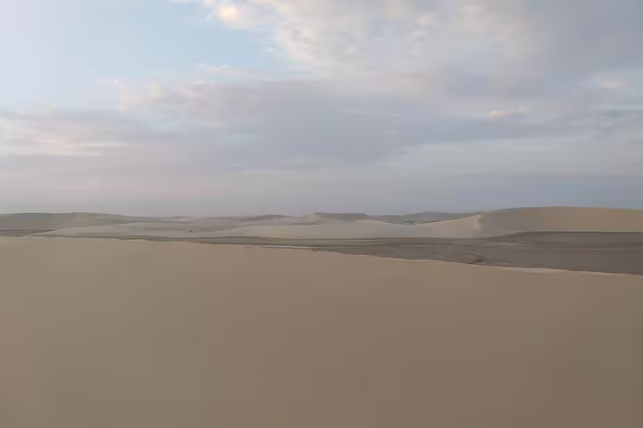 Vast golden sand dunes stretching under a cloudy sky during a Qatar desert safari adventure