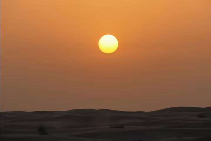 Golden sunset over sweeping Qatar desert sand dunes during a guided safari tour experience