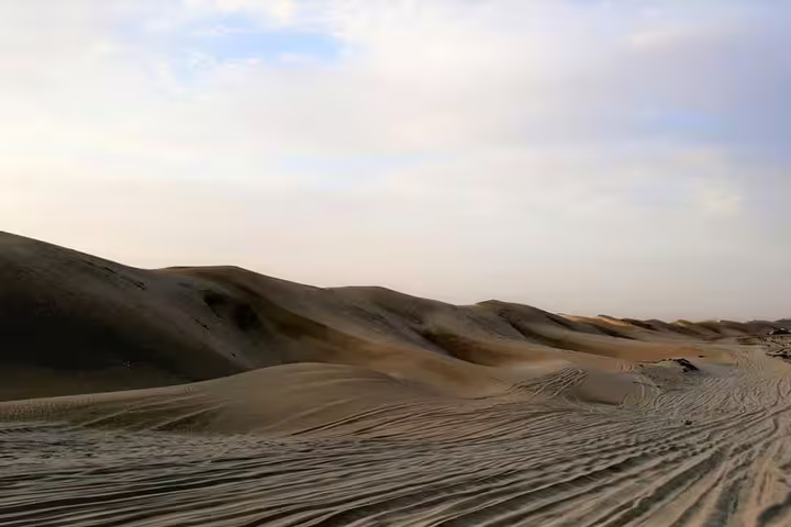 Expansive sand dunes under a clear sky highlight the serene beauty of Qatar's Inland Sea Desert landscape.