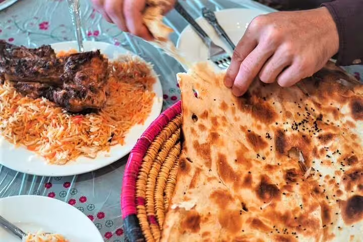 Close-up of traditional Qatari meal featuring lamb and rice with freshly baked bread, highlighting authentic flavors at Souq Waqif.