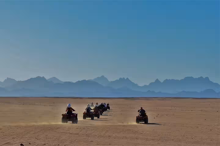 Group of riders on ATVs crossing the Sharm El Sheikh desert at sunrise, quad biking with mountain views