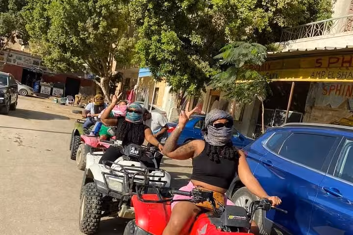 Riders on ATVs in Cairo village street wearing headscarves, starting quad bike adventure with shopping and lunch