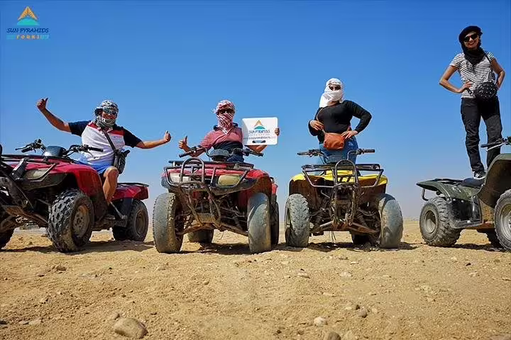 Friends posing on ATVs in the Giza desert, pyramids nearby, ideal 1-hour quad bike sunrise or sunset tour