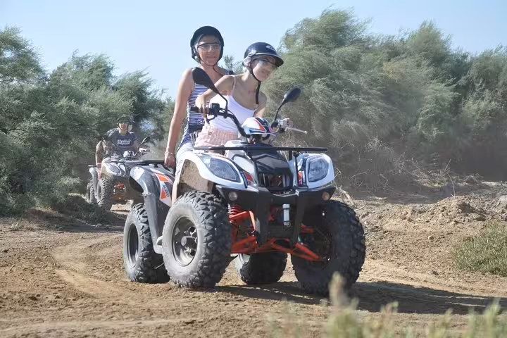 Two women on a quad bike exploring rugged trails surrounded by lush greenery in Kusadasi, Turkey.