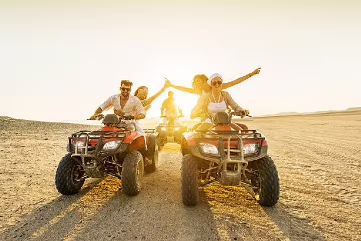 Friends riding quad bikes at sunset in Sinai Desert on private ATV safari tour from Sharm El Sheikh