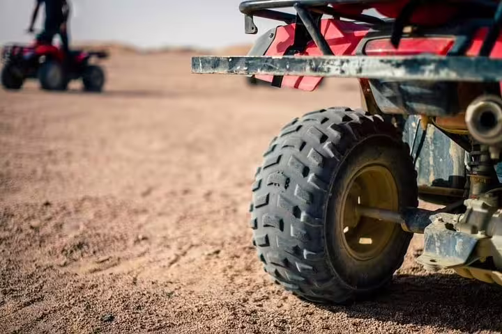 Close-up of quad bike tire on sandy desert terrain, highlighting off-road ATV ride on sunset safari