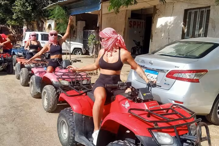 Tourists riding red quad bikes in Cairo desert, part of camel ride, lunch and shopping combo tour