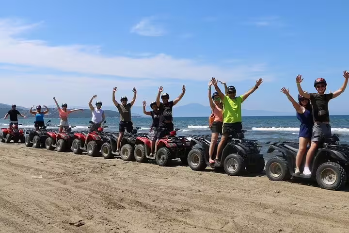 Group of happy tourists on quad bikes along a scenic beach, part of the Kusadasi Port cruise excursion adventure.