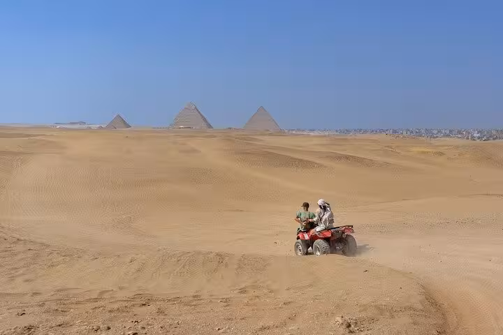 Quad biking in the Giza desert with the Pyramids in the distance, part of Cairo day tour with bazaar and cruise