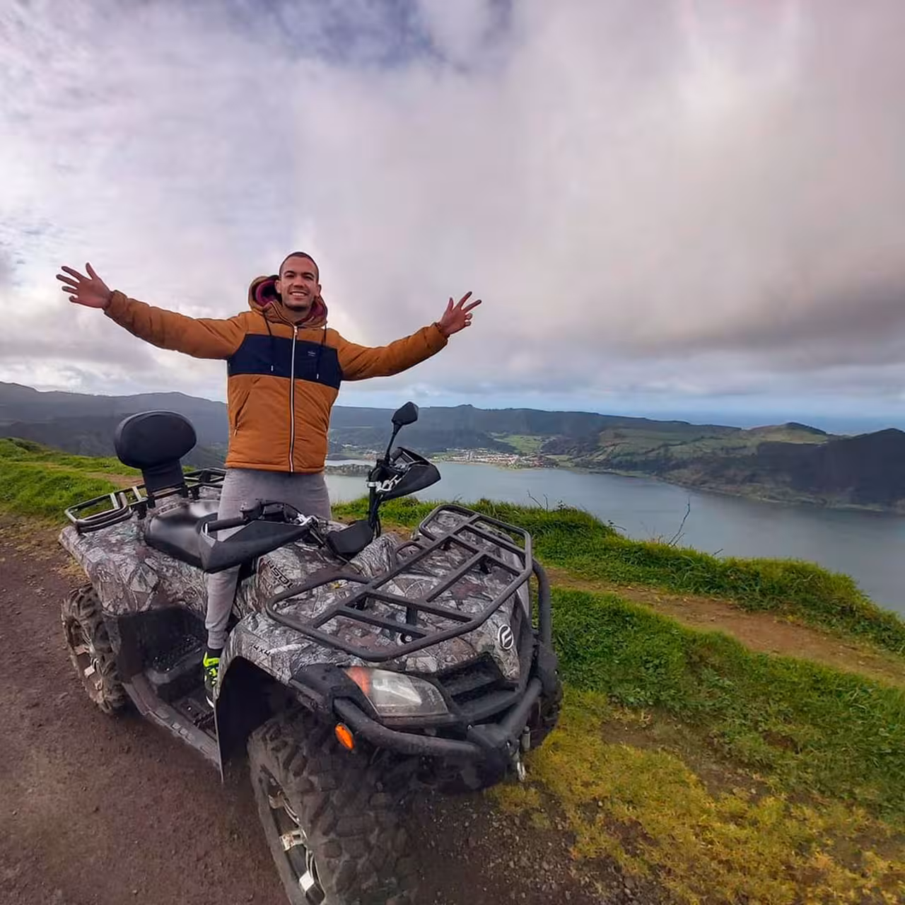 Happy rider standing on a quad overlooking Sete Cidades crater lake on an off‑road adventure tour in São Miguel, Azores