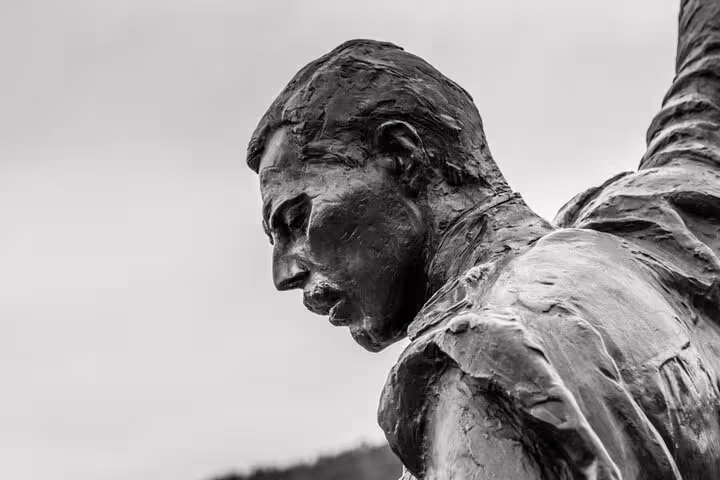 Bronze statue close-up profile view with raised arm against cloudy sky