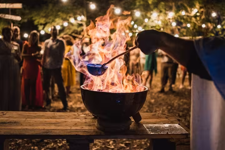 Vibrant queimada flames dance in a Santiago de Compostela outdoor show under string lights.