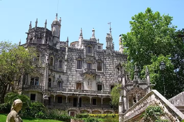 Majestic Gothic architecture of Quinta da Regaleira in Sintra, Portugal, surrounded by lush greenery on a sunny day.