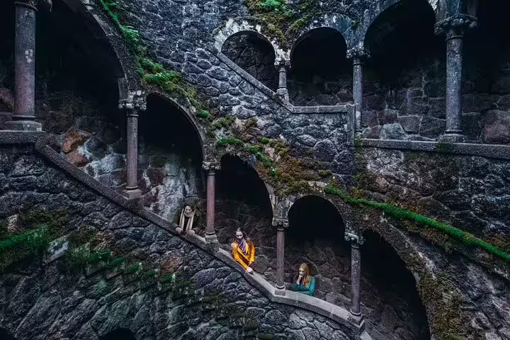 Tourists explore the enchanting spiral staircase of Quinta da Regaleira, a highlight of the Sintra, Cascais & Estoril Private Tour.